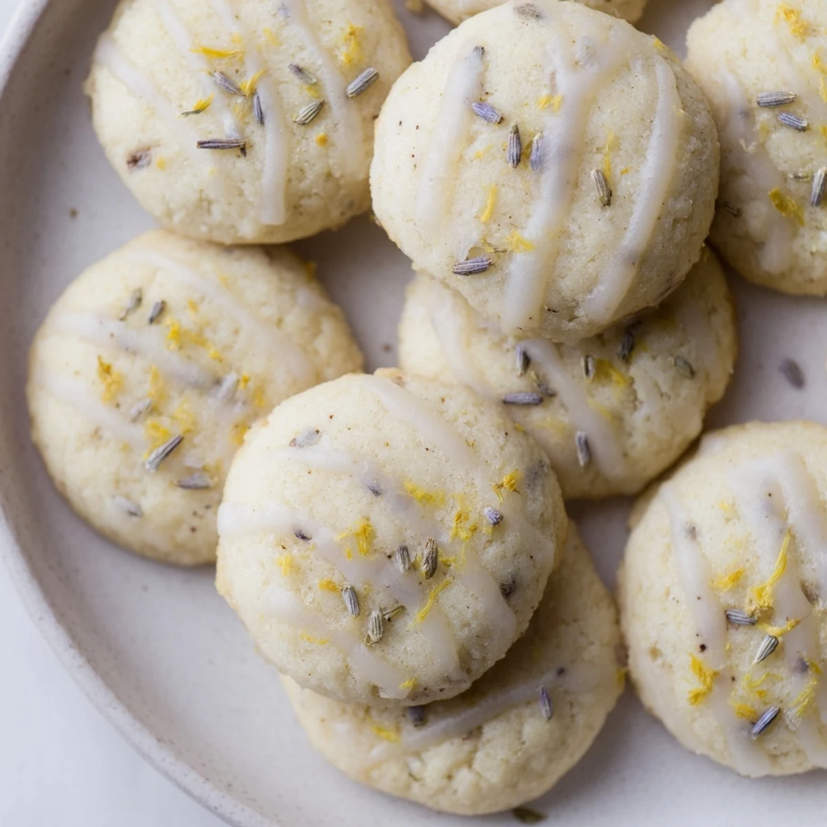 Pale purple-flecked Lemon Lavender Cookies cooling on wire rack with citrus zest visible