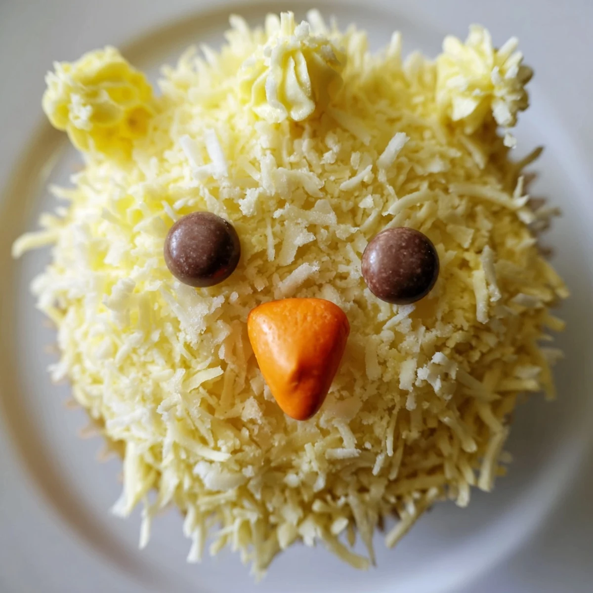 Festive Easter Chick Cupcakes topped with swirled buttercream, chocolate chip eyes, and orange beaks