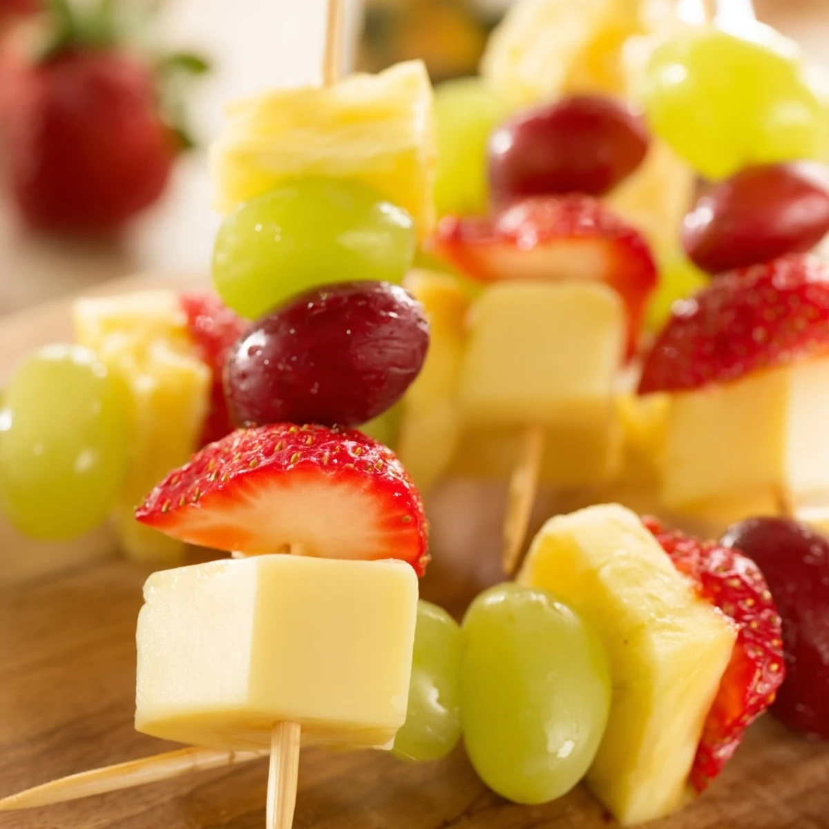 Fruit and cheese kabobs featuring red grapes pineapple strawberries and cheddar cubes on skewers