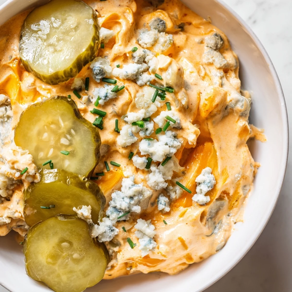 Tangy buffalo pickle dip topped with fresh chives and sliced dill pickles