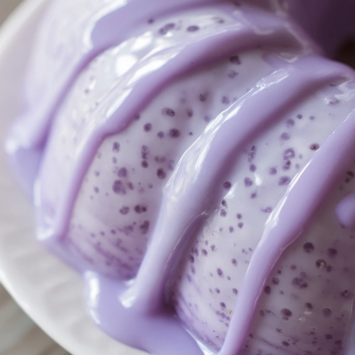 Glossy lavender glaze pooling on a ceramic plate beside scattered purple lavender buds