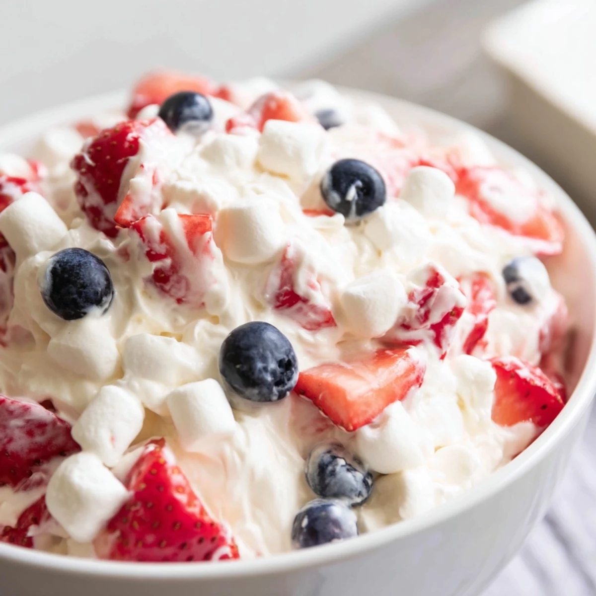 Red white blue cheesecake salad scooped into a chilled glass bowl
