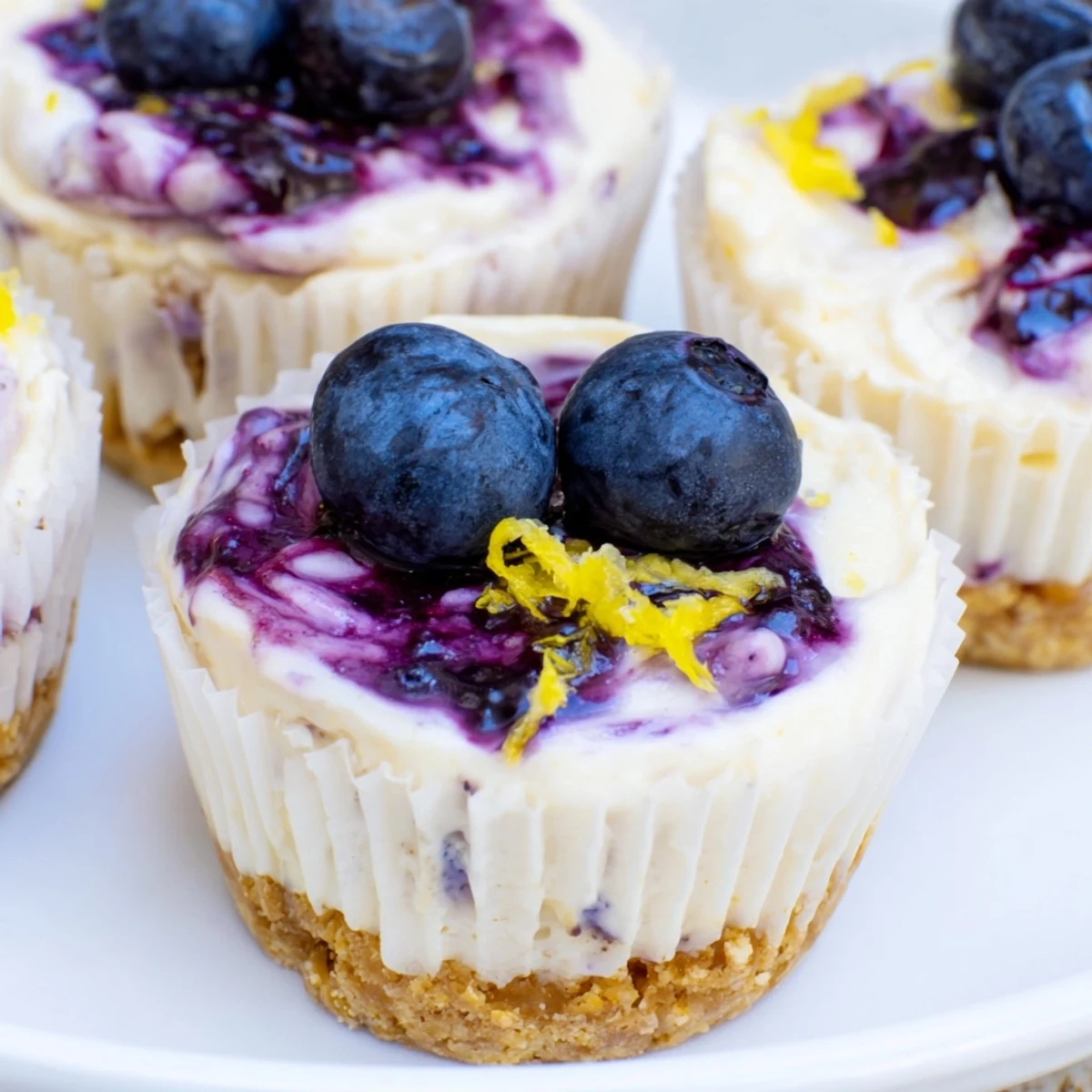 Golden graham cracker crusts filled with tangy mini lemon blueberry cheesecakes swirled with berry sauce