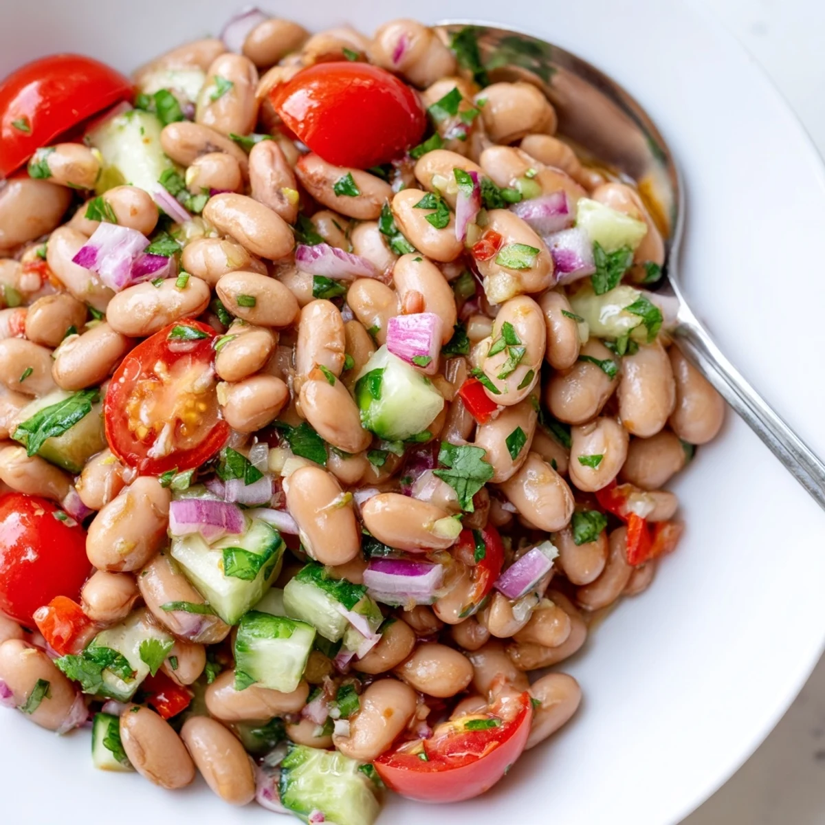 Colorful pinto bean salad loaded with ripe tomatoes and crunchy vegetables in a bright bowl