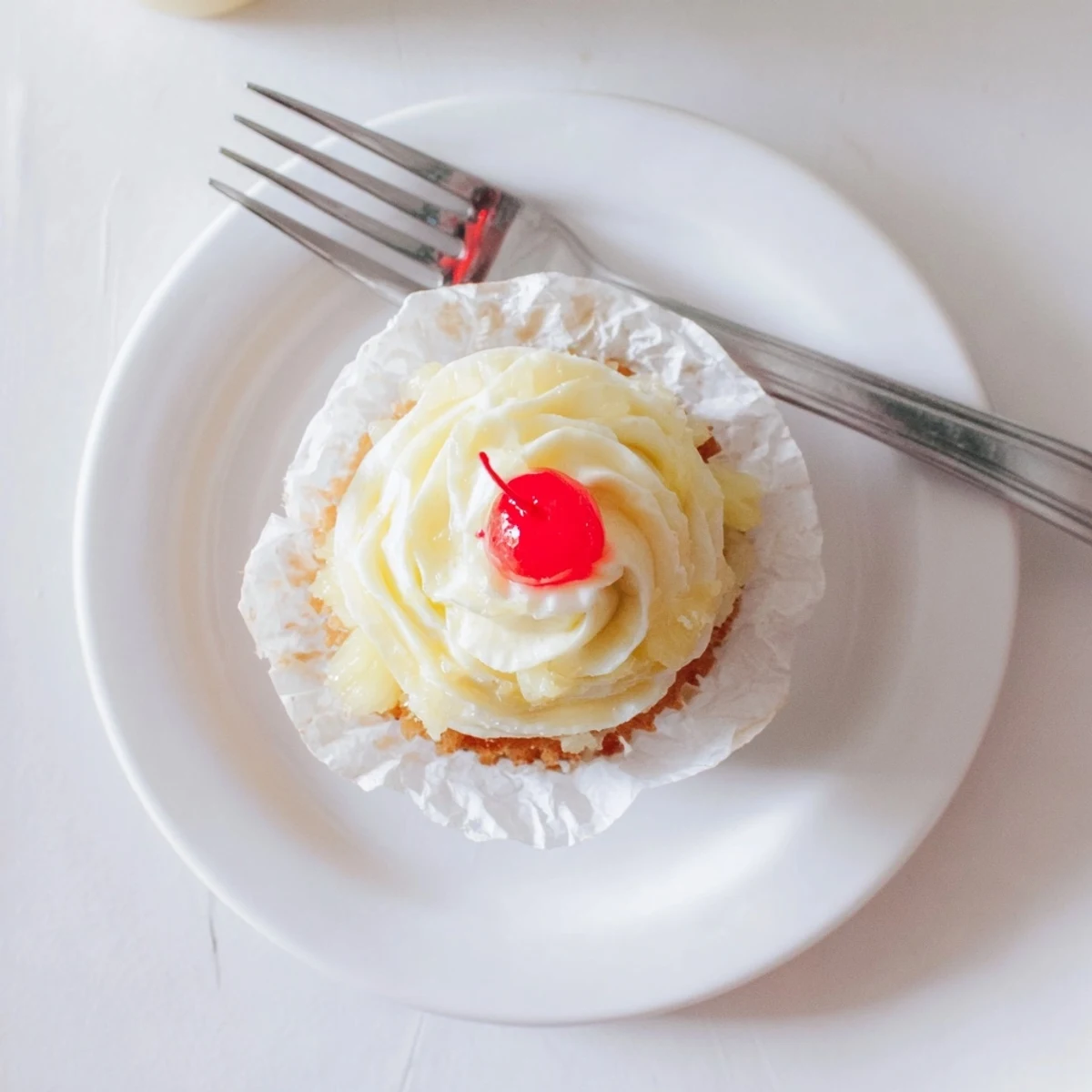 Golden Dole Whip Cupcakes topped with fluffy pineapple whipped frosting and cherry garnish