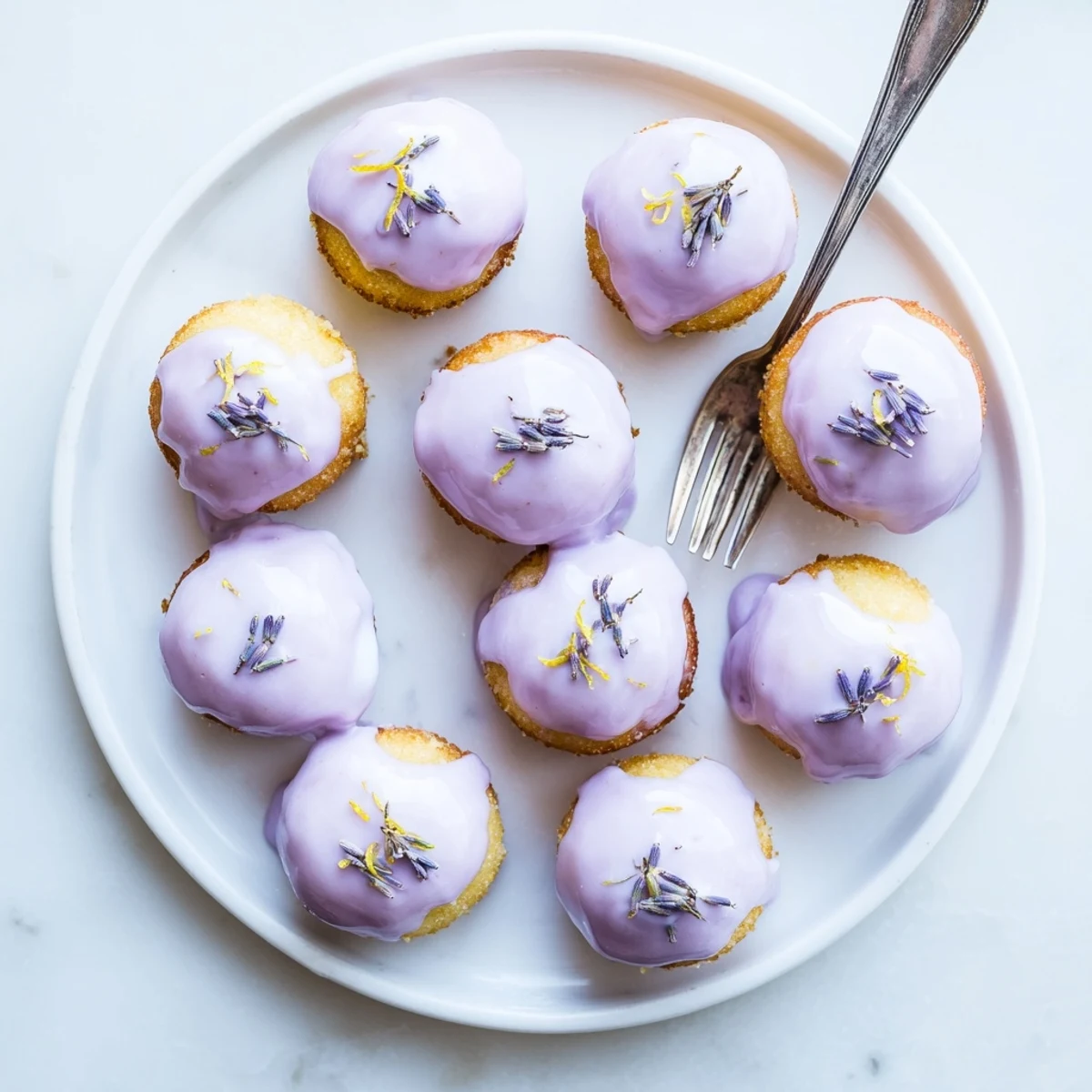 Mini lemon cakes with lavender glaze arranged on a vintage dessert plate