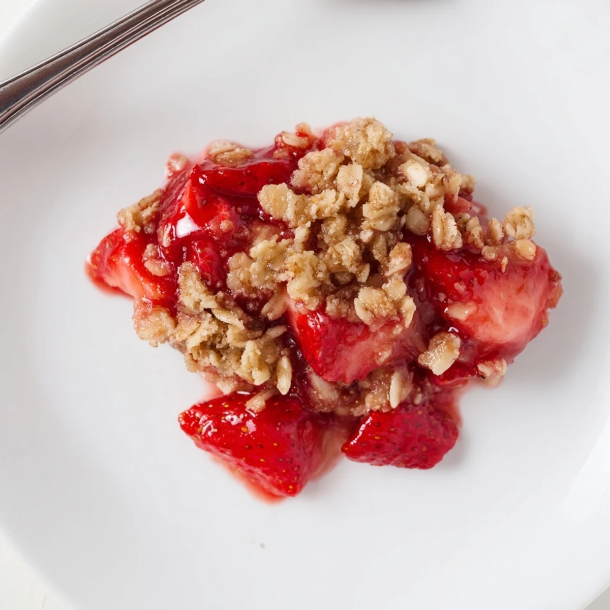 Warm Fresh Strawberry Crisp in baking dish, vanilla ice cream melting.