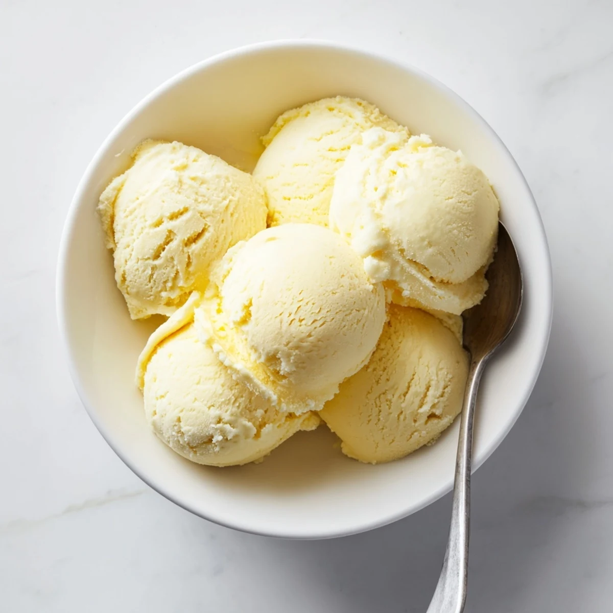 Creamy homemade vanilla ice cream recipe scooped into a glass bowl topped with fresh berries