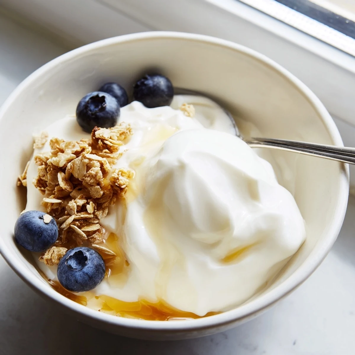 Creamy homemade yogurt served in glass jars topped with fresh berries