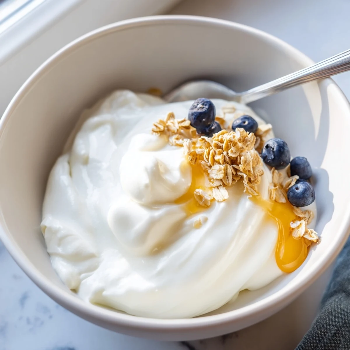 Smooth homemade yogurt in a white bowl garnished with sliced ripe fruit