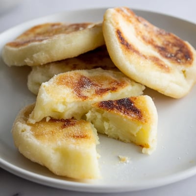 Thick slice of warm Irish Potato Bread Farl drizzled with melted butter, steam rising from its fluffy, potato-based interior.  