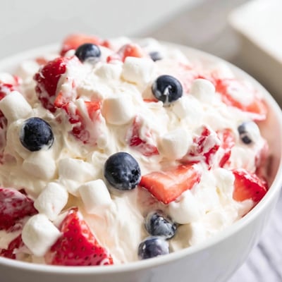 Red white blue cheesecake salad scooped into a chilled glass bowl